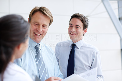 Buy stock photo Smiling business executives going through documents together in an informal meeting 