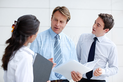 Buy stock photo Business associates going through documents together in an informal meeting 