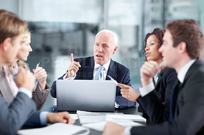 Buy stock photo Corporate executives sitting at a table during a meeting and using a laptop 