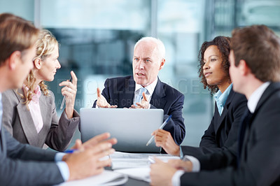 Buy stock photo Business executives sitting at a table during a meeting and using a laptop 