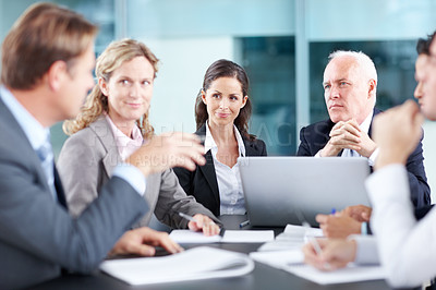 Buy stock photo Thoughtful executives sitting at a table during a meeting and using a laptop 