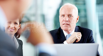 Buy stock photo Focused senior executive listening to his colleagues in a meeting while sitting with a laptop