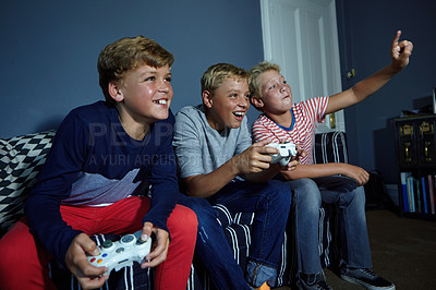 Buy stock photo Shot of young boys playing video games