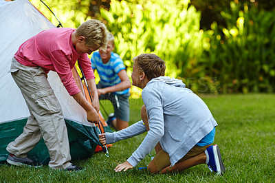 Buy stock photo Shot of three young boys putting up their tent