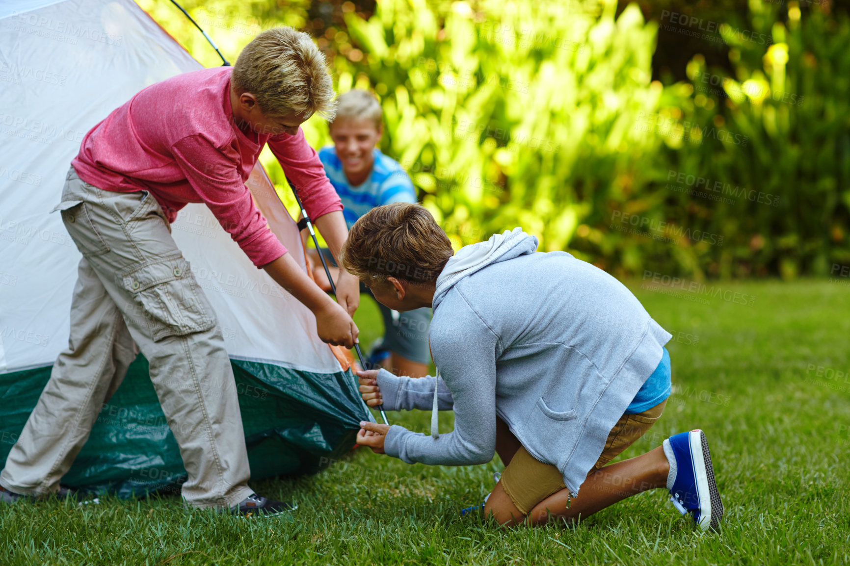 Buy stock photo Shot of three young boys putting up their tent