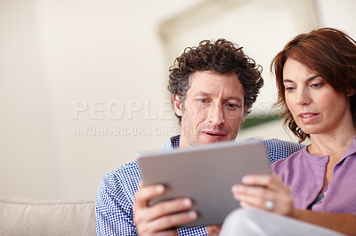 Buy stock photo Shot of a couple using a tablet  while relaxing at home