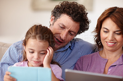 Buy stock photo Shot of a little girl using a digital tablet white sitting with her parents