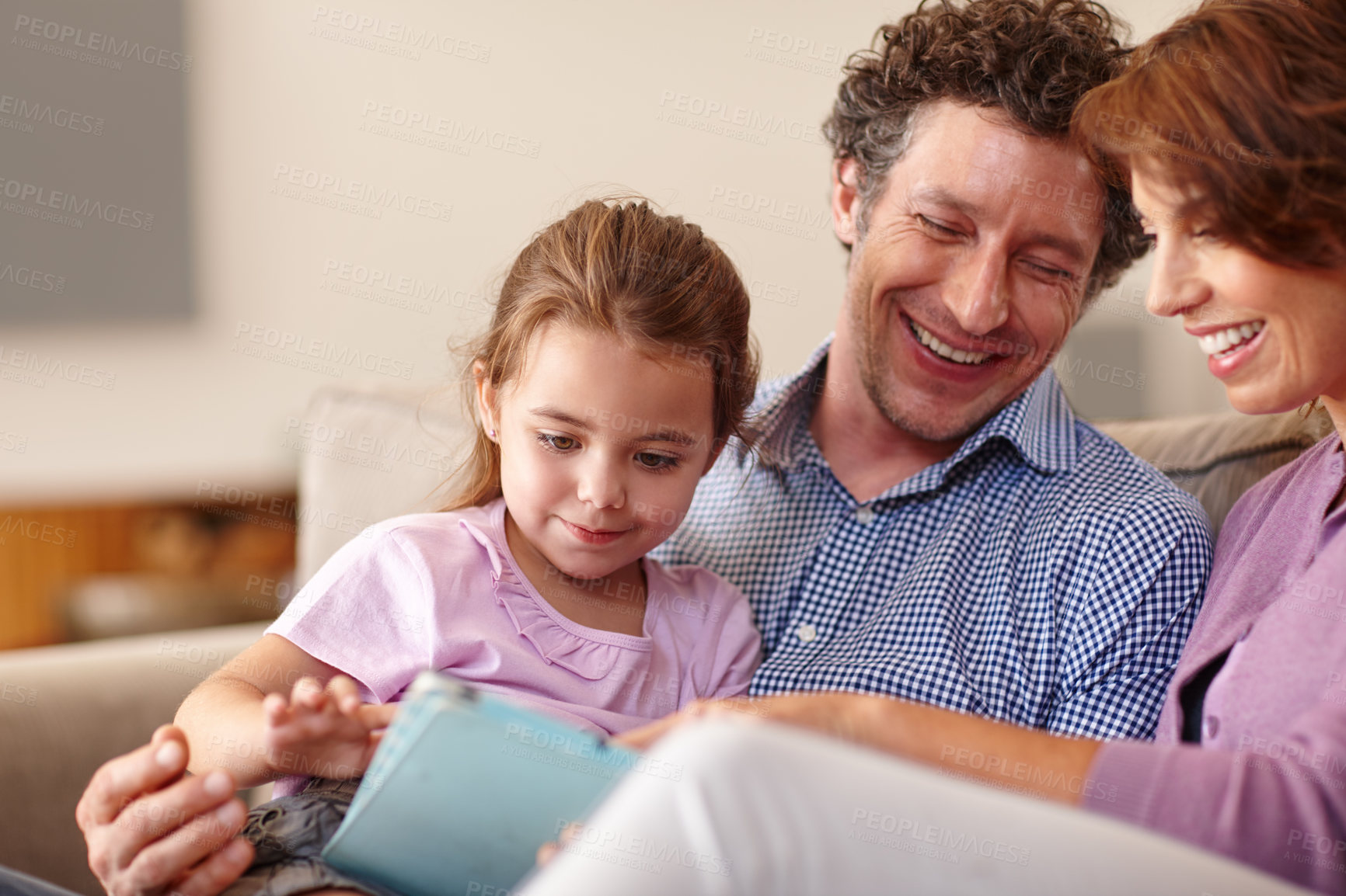 Buy stock photo Shot of a little girl using a digital tablet white sitting with her parents