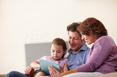 Buy stock photo Shot of a little girl using a digital tablet white sitting with her parents