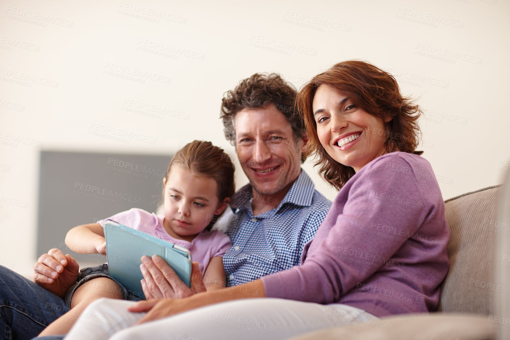 Buy stock photo Shot of a little girl using a digital tablet white sitting with her parents