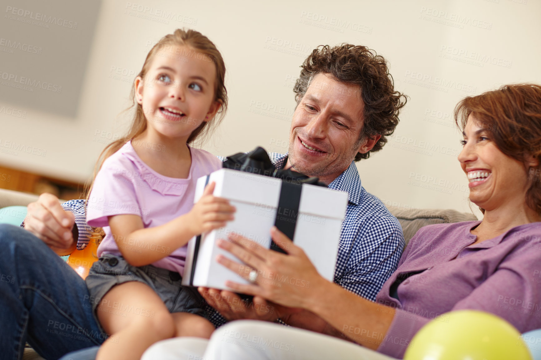 Buy stock photo Shot of a family siting in the living room with a gift