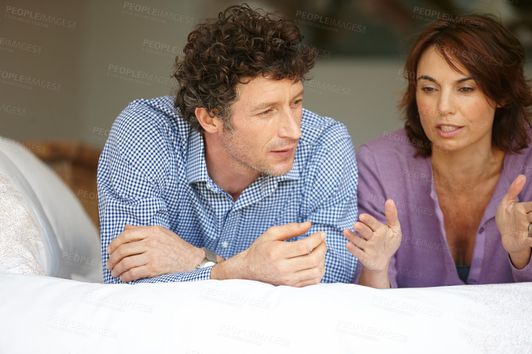 Buy stock photo Shot of a couple having a conversation on their bed