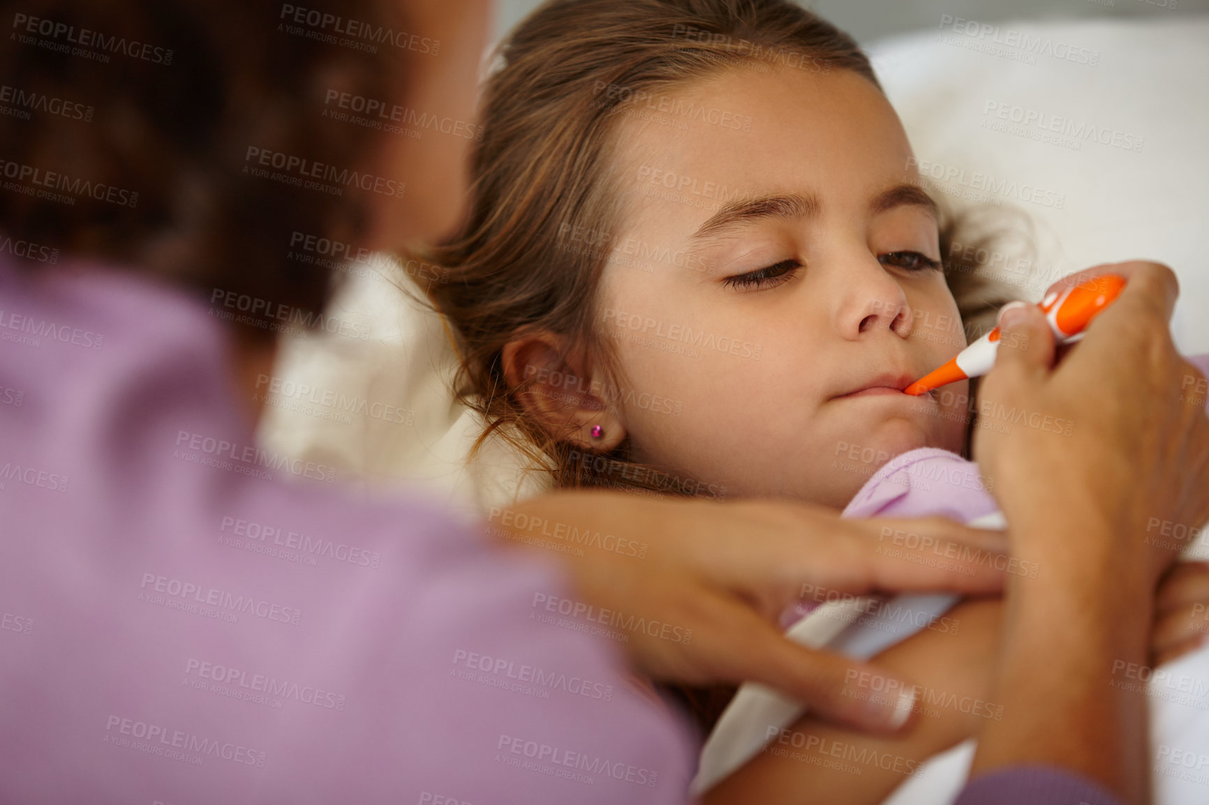 Buy stock photo Shot of a little girl lying in bed while her mother takes her temperature with a thermometer