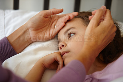 Buy stock photo Shot of a caring mother feeling the forehead of her sick little girl