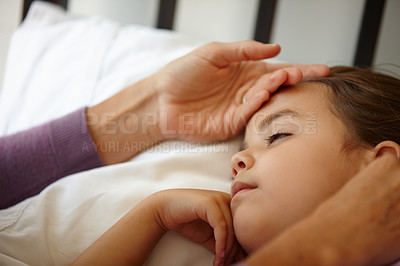 Buy stock photo Shot of a caring mother feeling the forehead of her sick little girl