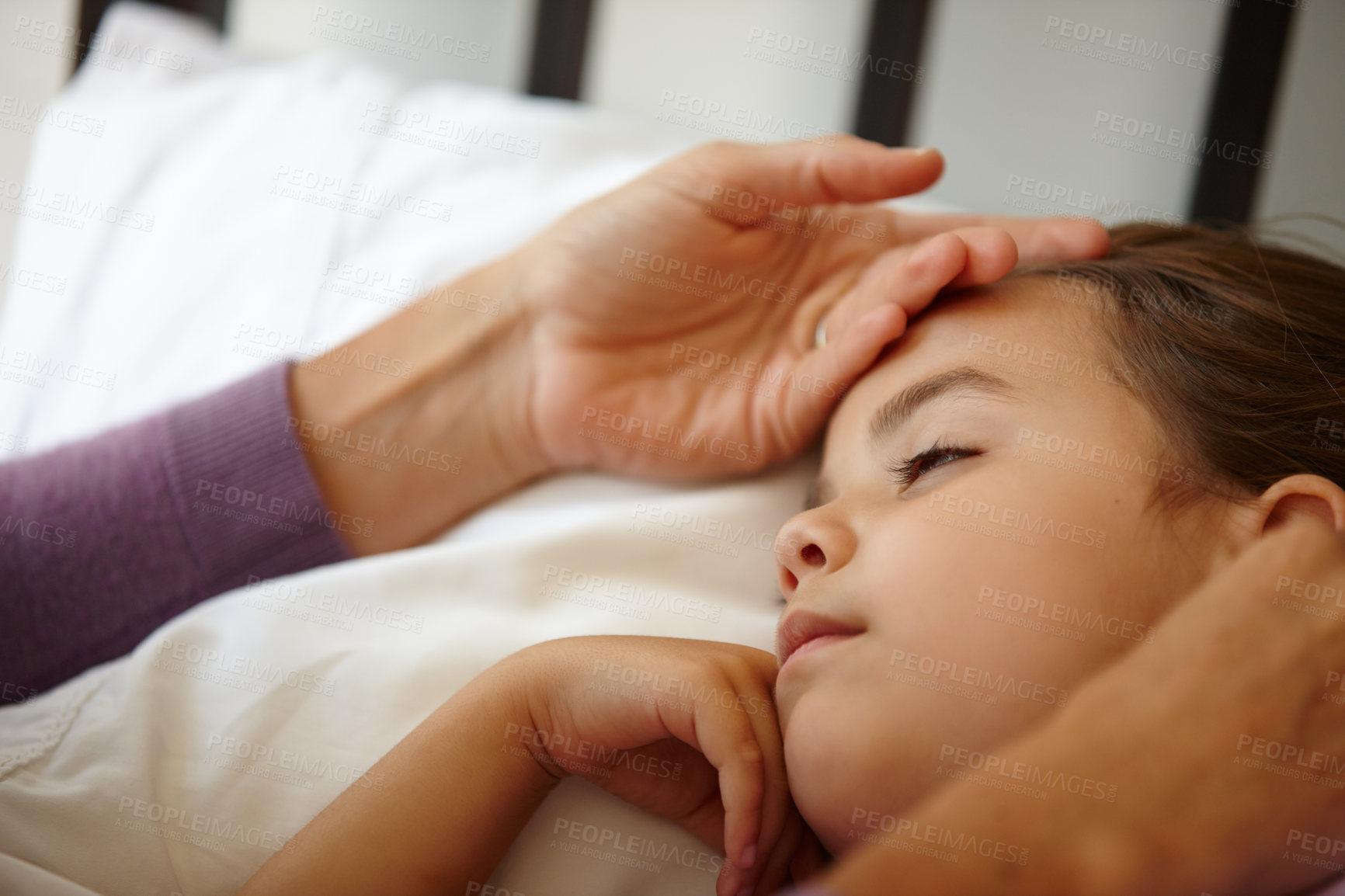 Buy stock photo Shot of a caring mother feeling the forehead of her sick little girl