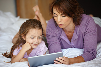 Buy stock photo Shot of a mother and daughter using a digital tablet together at home