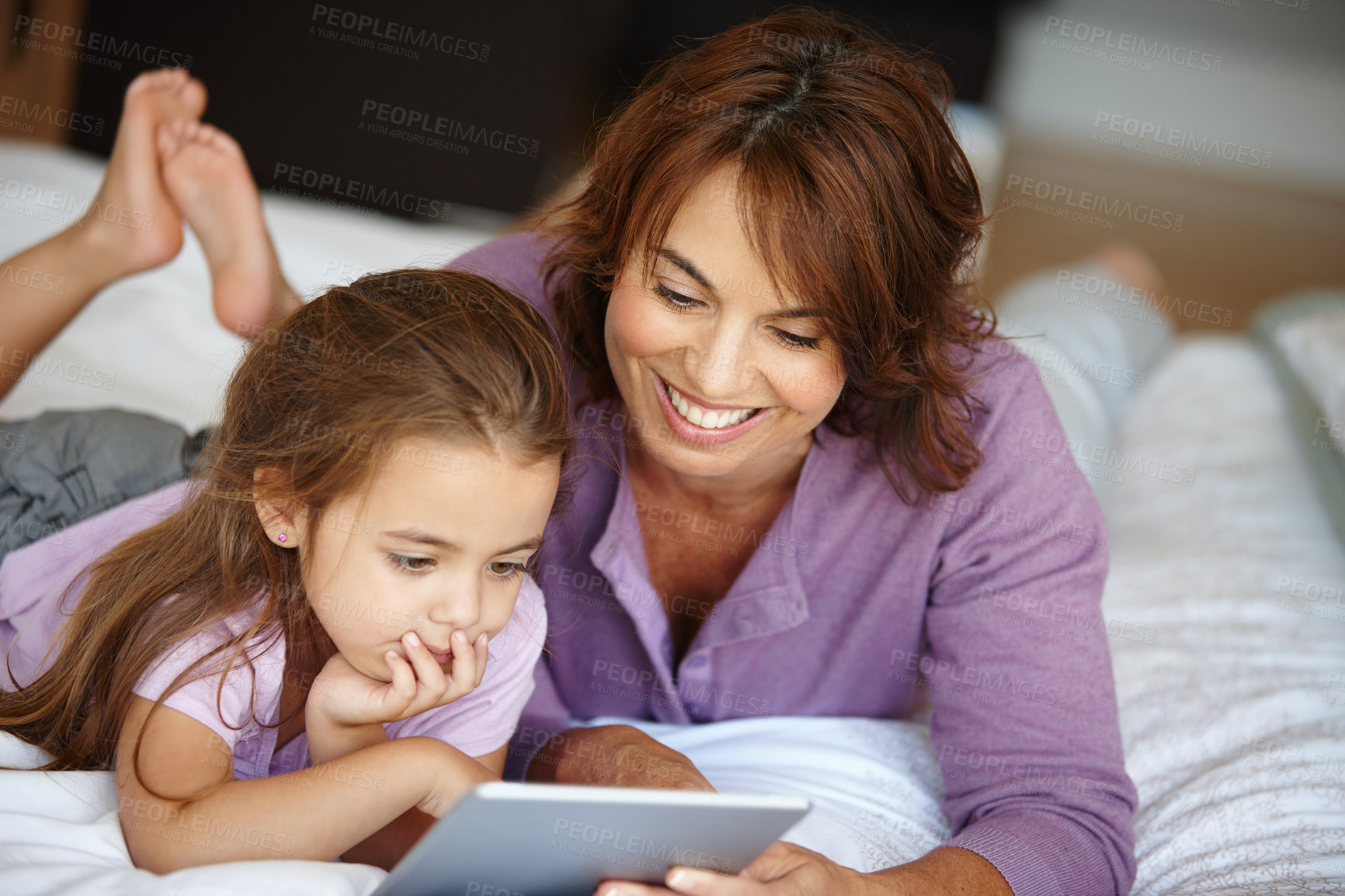 Buy stock photo Shot of a mother and daughter using a digital tablet together at home