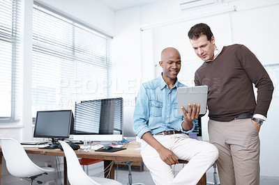 Buy stock photo Two businessmen working on a digital tablet in the office