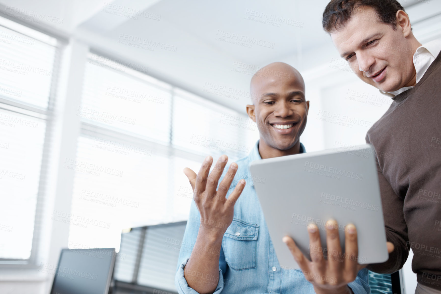 Buy stock photo Two business colleagues sharing a digital tablet in the office