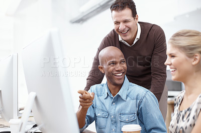 Buy stock photo A young businessman pointing out something to his colleague while their boss looks on