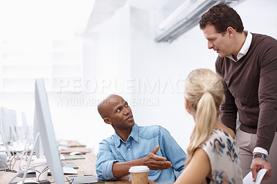 Buy stock photo Two colleagues talking to their boss while working hard in the office