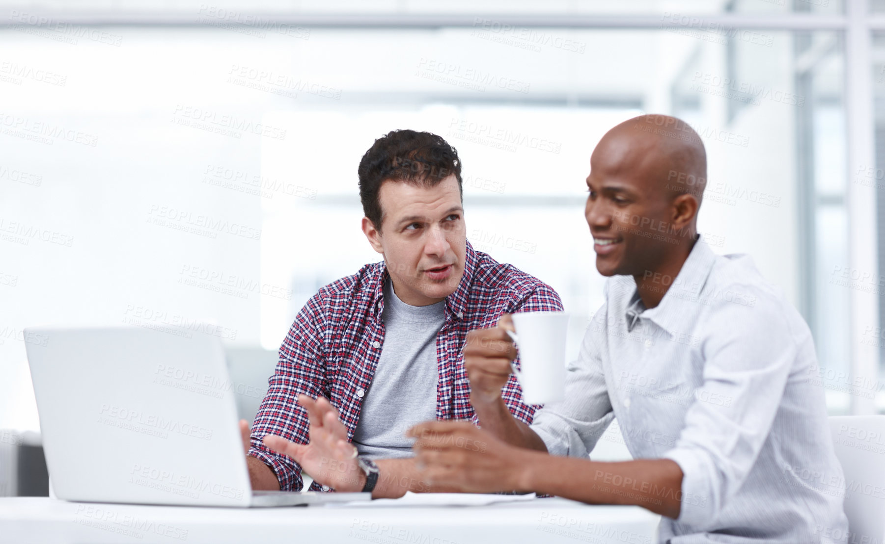 Buy stock photo Two professionals having a work discussion while seated at a desk with a laptop