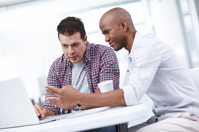 Buy stock photo Two businessmen working together on a project on a laptop while seated at a table