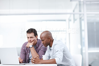 Buy stock photo Two serious businessmen working together on a project on a laptop