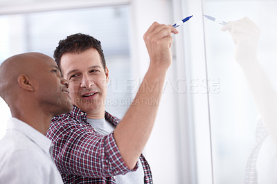 Buy stock photo A businessman explaining a concept to a junior co-worker on a whiteboard