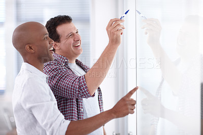 Buy stock photo A businessman explaining a concept to a junior colleague on a whiteboard