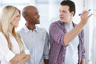Buy stock photo A senior partner explaining something to his colleagues on a whiteboard with a marker