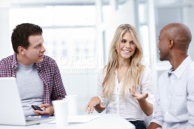 Buy stock photo Three designers having a productive meeting while seated at a table with a laptop