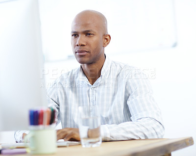 Buy stock photo Shot of a serious-looking african american designer at work on a desktop computer in the office