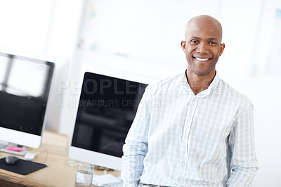 Buy stock photo Portrait of an handsome african american designer leaning against a desk lined with computers and smiling at the camera