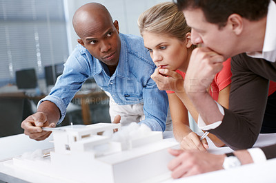 Buy stock photo A team of architects looking thoughtful while working together on an architectural model
