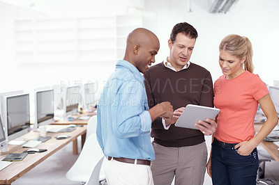 Buy stock photo Three businesspeople sharing a digital tablet in the workplace