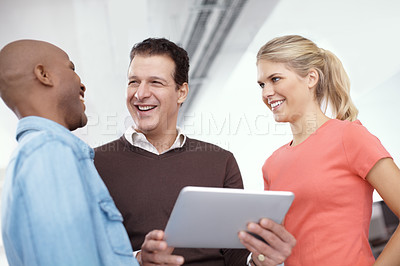 Buy stock photo Three business colleagues sharing a digital tablet in the office