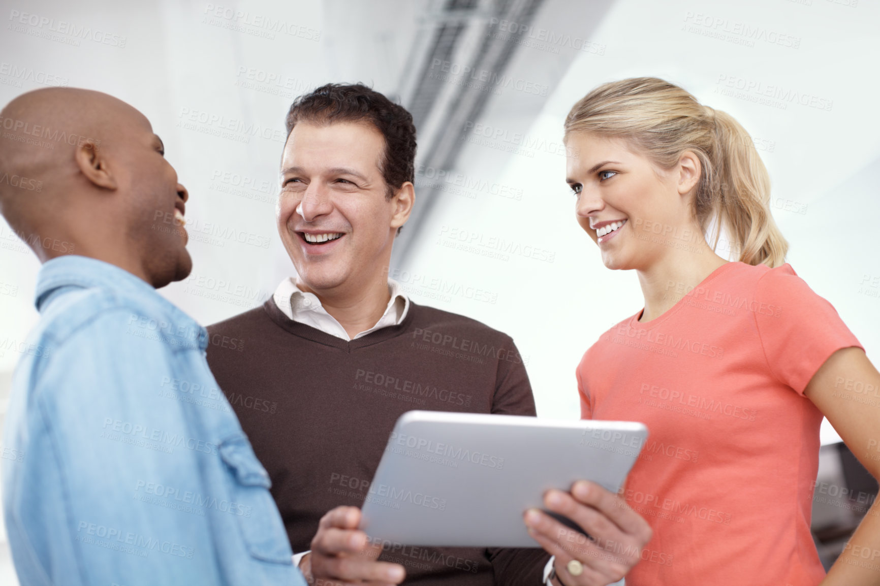 Buy stock photo Three business colleagues sharing a digital tablet in the office