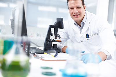 Buy stock photo A researcher smiling while sitting at a table in front of a microscope and computer
