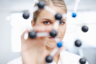 Buy stock photo Portrait of a gorgeous female scientist looking through a molecular structure model