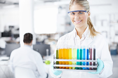 Buy stock photo Portrait of a beautiful young scientist carrying a tray of test tubes with a male colleague in the background