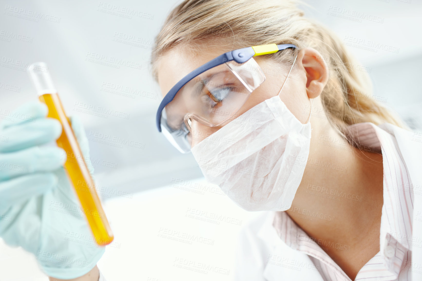 Buy stock photo Closeup of a female scientist looking at a test tube filled with liquid 