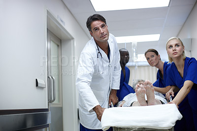 Buy stock photo A team of doctors pushing a patient down the passage