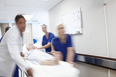 Buy stock photo A team of doctors rushing a patient down the hallway