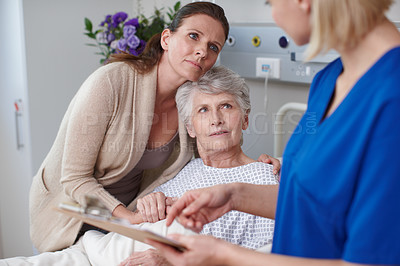 Buy stock photo A daughter and her mother looking at the medical report being shown to them by a young nurse