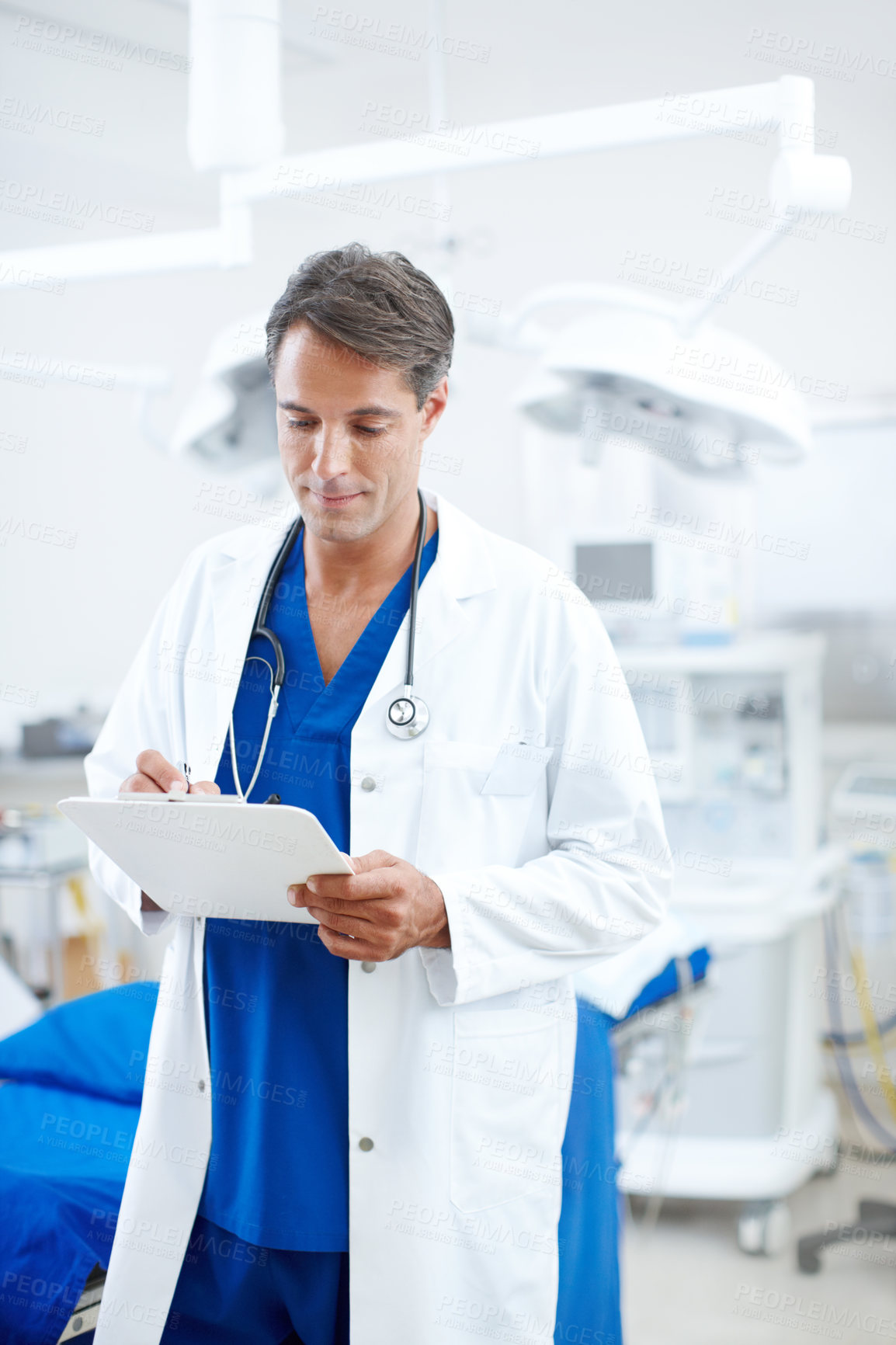 Buy stock photo A confident male doctor reading and marking a chart in the hospital