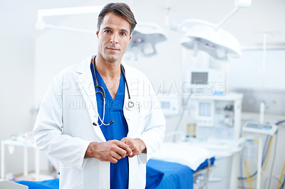 Buy stock photo A confident male doctor standing infront of the operating table in the hospital