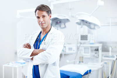 Buy stock photo A confident male doctor standing with his arms crossed in the operating room