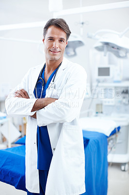 Buy stock photo A happy male doctor standing with his arms crossed in the operating room